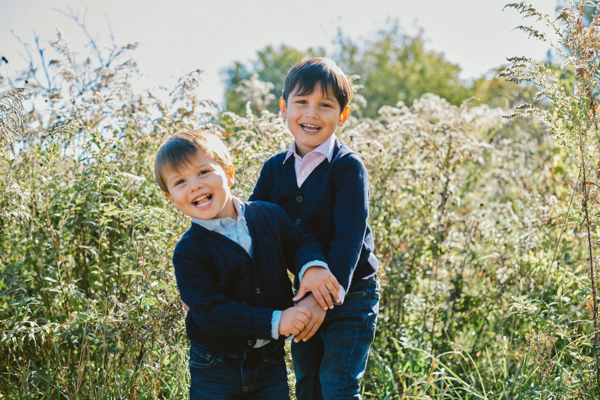 Two children smiling in a field. Image taken by lifestyle commercial photographer Hannah Dunsirn, located in Los Angeles.